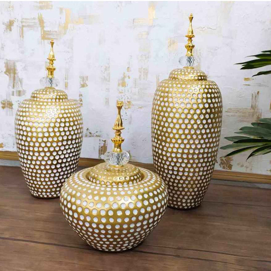Three gold ceramic vases with textured design on a wooden surface.