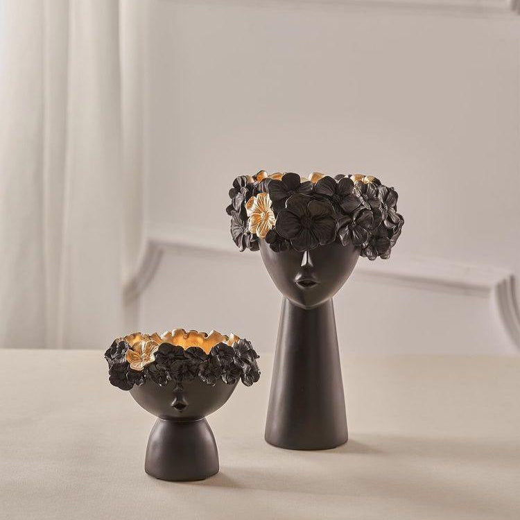 Two black ceramic vases with face designs on a light background
