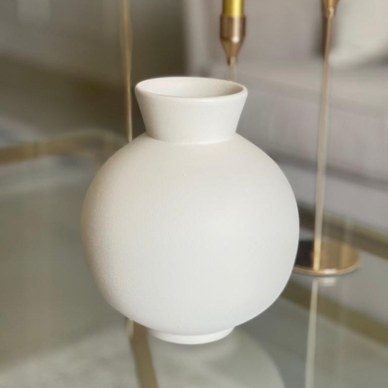 White vase on a reflective surface with a blurred background