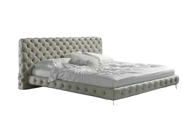 Modern bedroom with a gray tufted bed and white drapes.