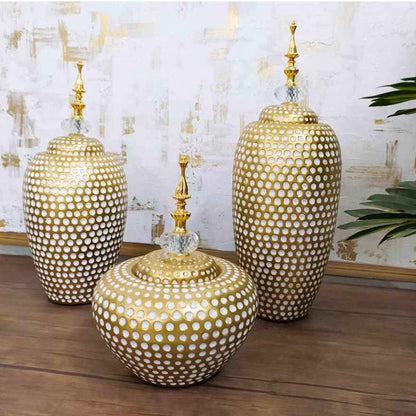 Three gold ceramic vases with textured design on a wooden surface.