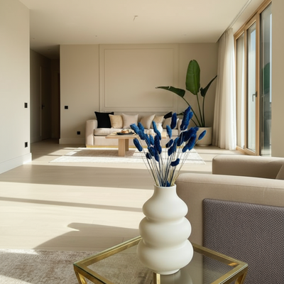 Modern living room with a vase of blue flowers on a glass table.