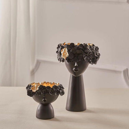 Two black ceramic vases with face designs on a light background