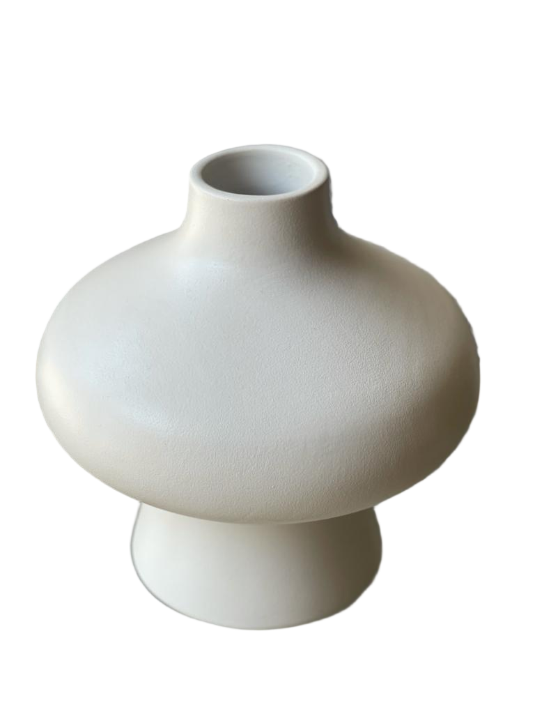 White ceramic vase on a reflective surface with a blurred background