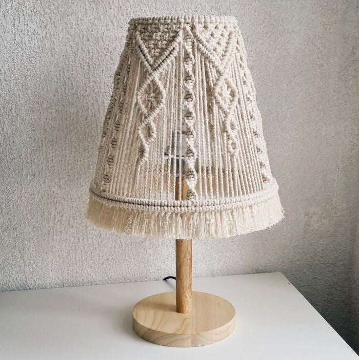 Lamp with a macrame shade on a white surface against a gray wall