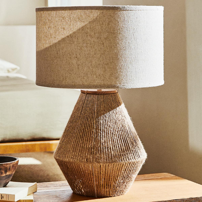 Woven lamp with a geometric design on a wooden surface.