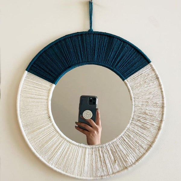 Round mirror with blue and white frame on a beige wall
