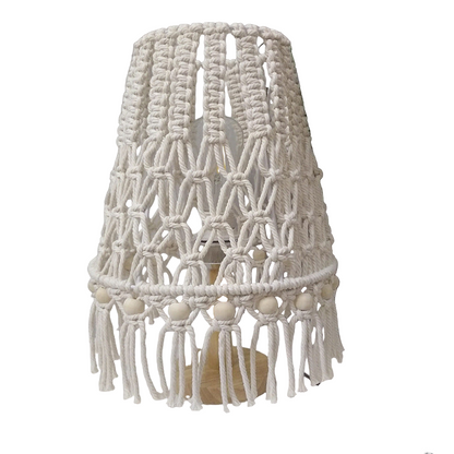 Macrame-style lampshade on a white surface with a plant in the background