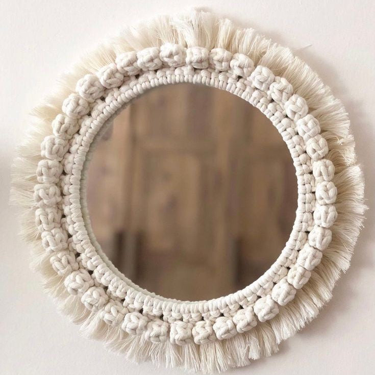 Round mirror with macrame frame on a white wall