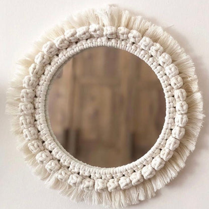 Round mirror with macrame frame on a white wall