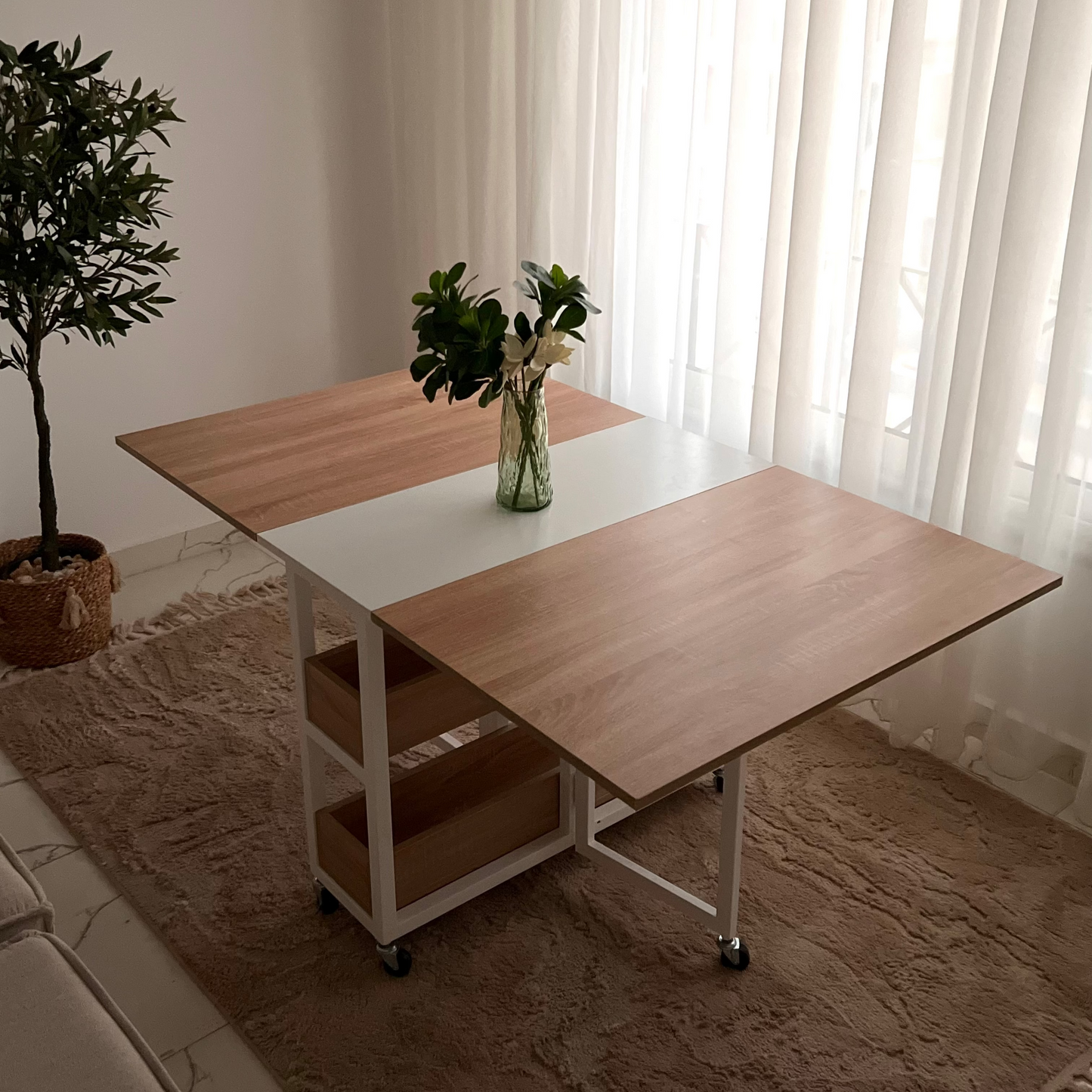 Wooden desk with a white top in a room with curtains and a plant.
