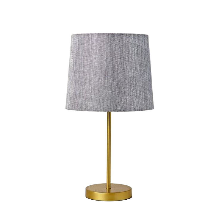 Table lamp with a gray shade and gold base on a white brick wall background