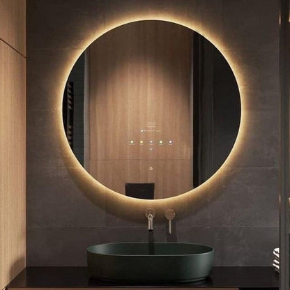 Round illuminated bathroom mirror with a dark sink below on a tiled wall.